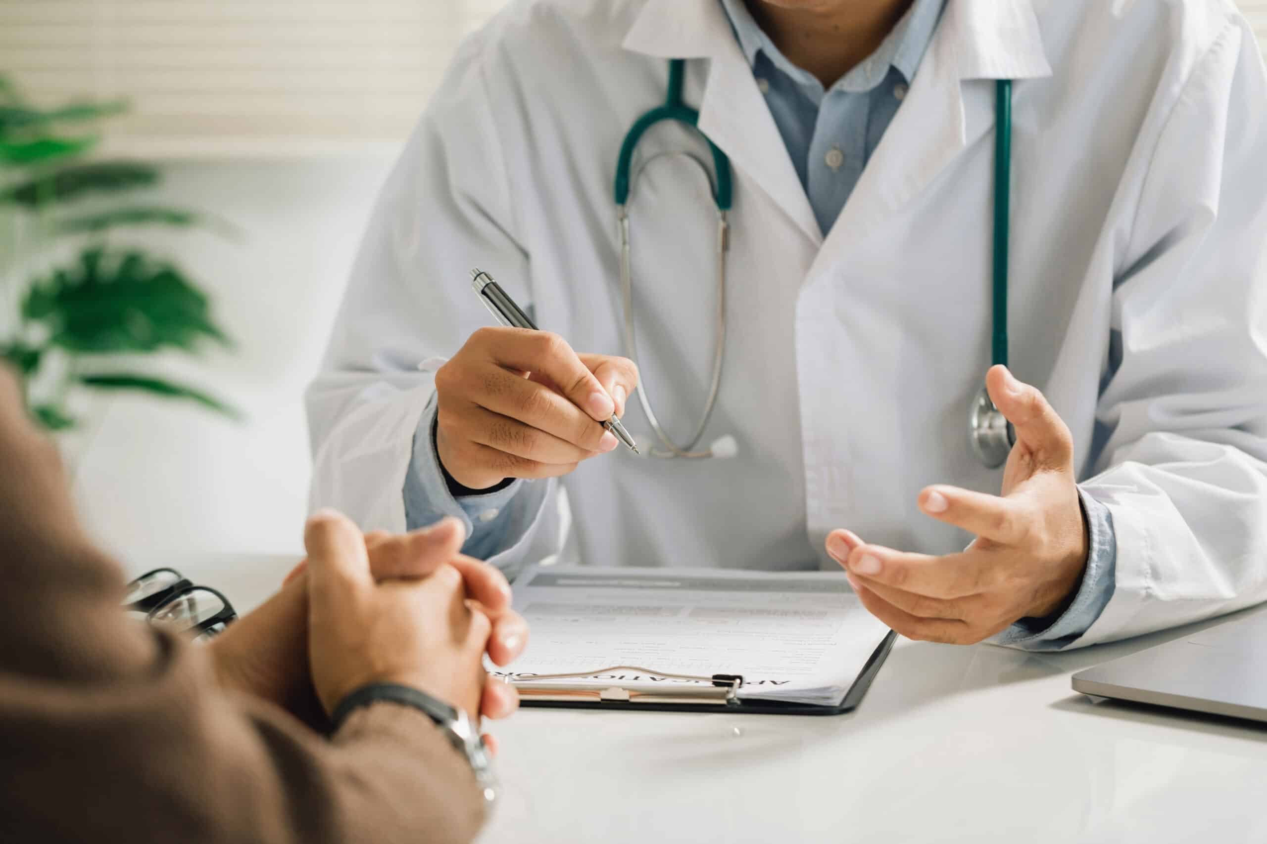 Arzt in weißem Kittel erklärt einem Patienten anhand von Unterlagen einen Befund – einfühlsame und umfassende medizinische Aufklärung in der Praxis Dr. med. Erdmute Kunstmann